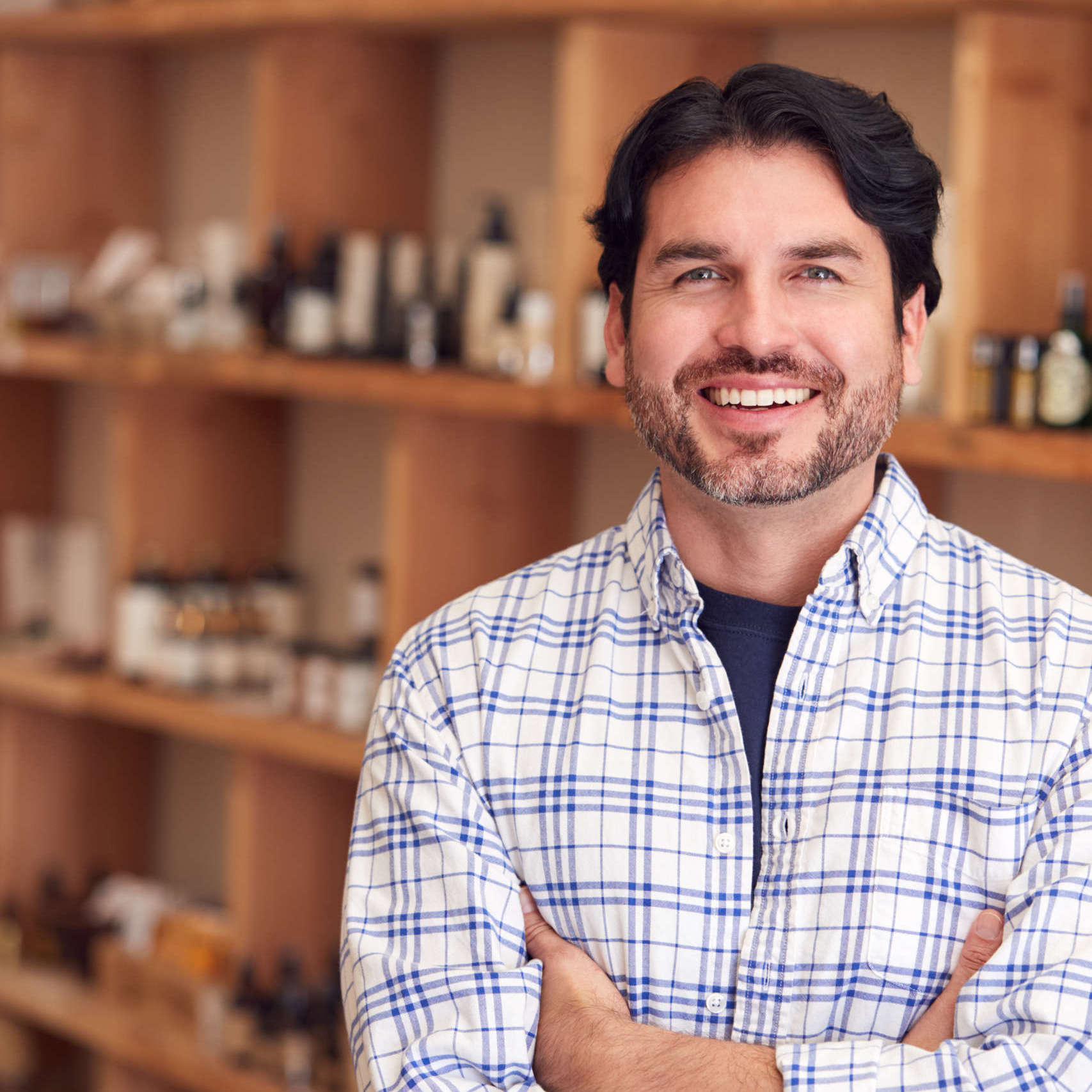 Portrait Of Male Owner Of Gift Store Standing In Front Of Shelves With Cosmetics And Candles